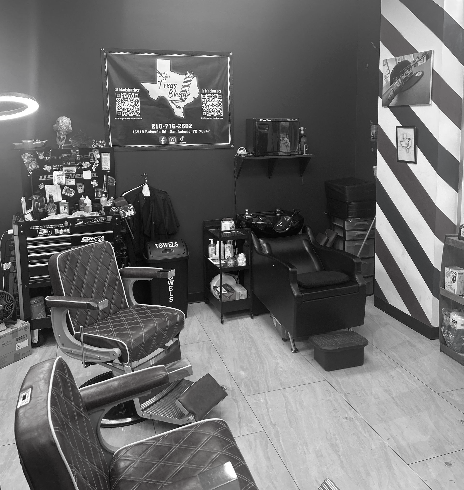 Black and white barbershop interior, featuring chairs, stations, and decor.