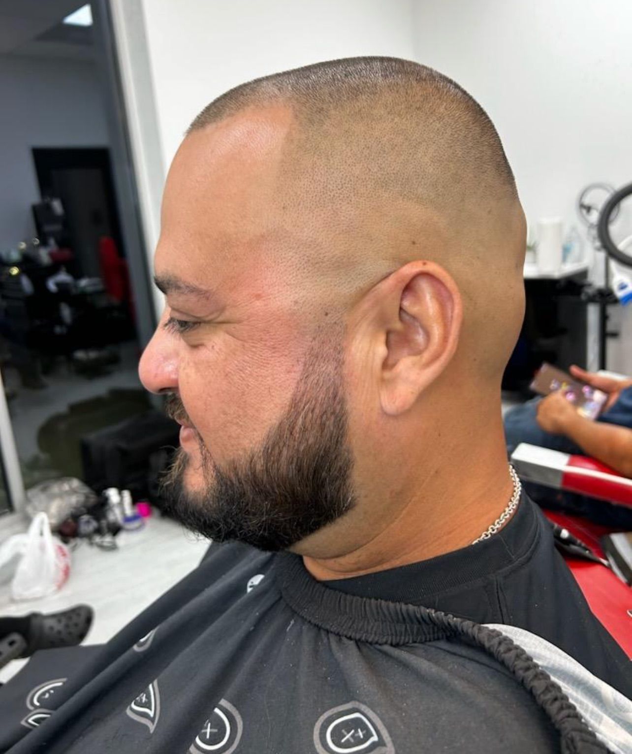 Man with a shaved head and beard in a barber shop.