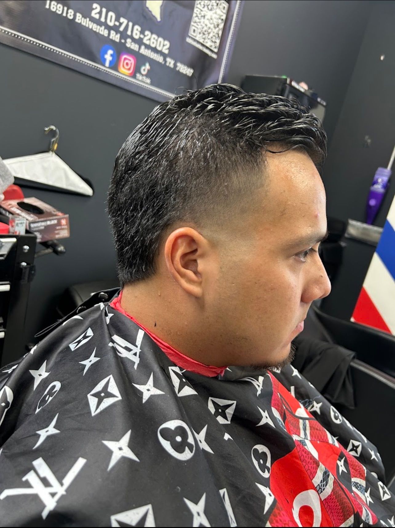 Man with fresh haircut in a barbershop; skin fade, textured top.