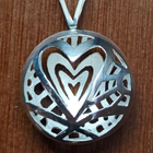 Zilveren hanger met een opengewerkt cirkelvormig ontwerp, hartvorm.