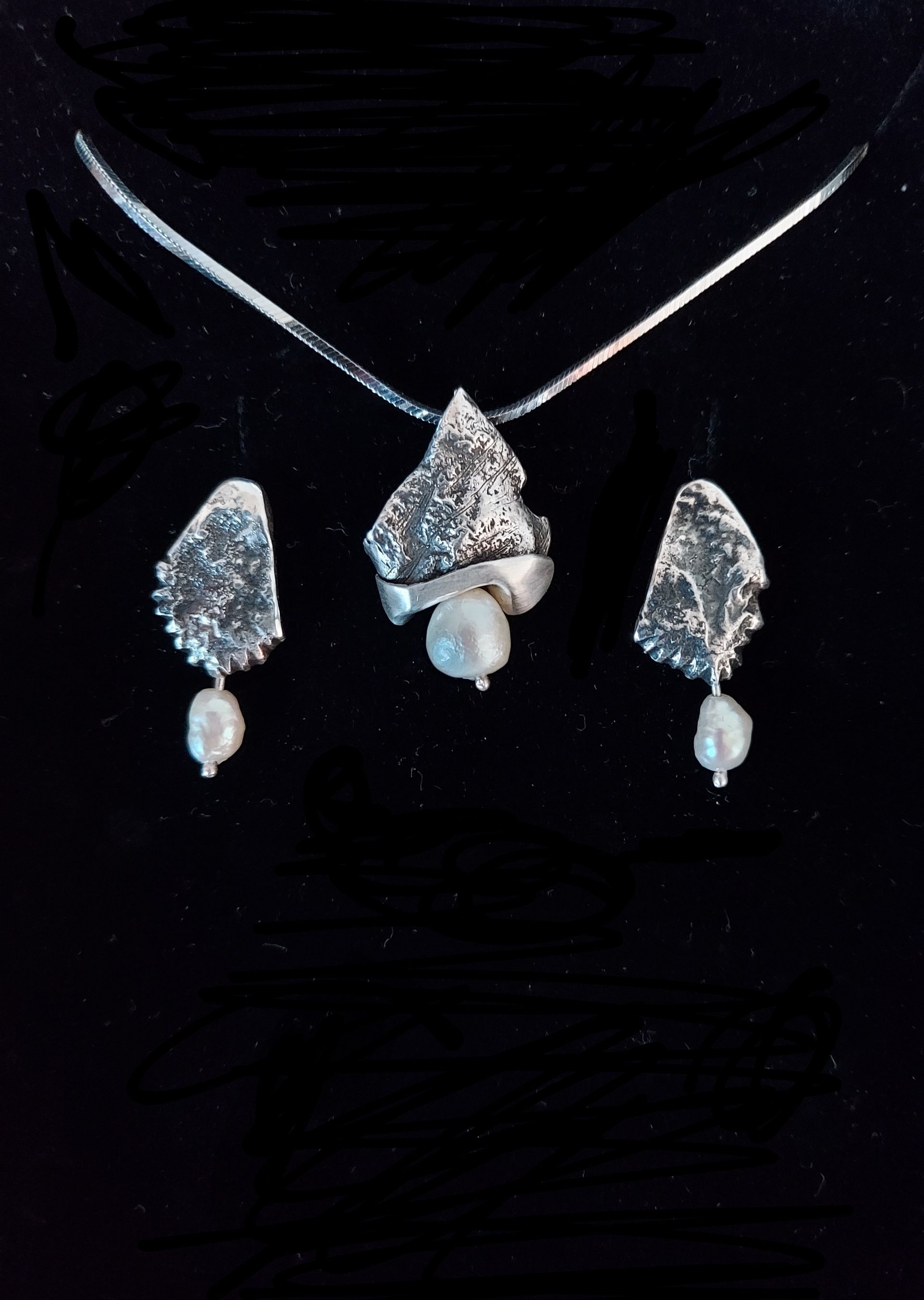 Zilveren sieradenset met zoetwaterparel. ketting en oorbellen, zilver is ruw en strak gecombineerd bewerkt boven de parels