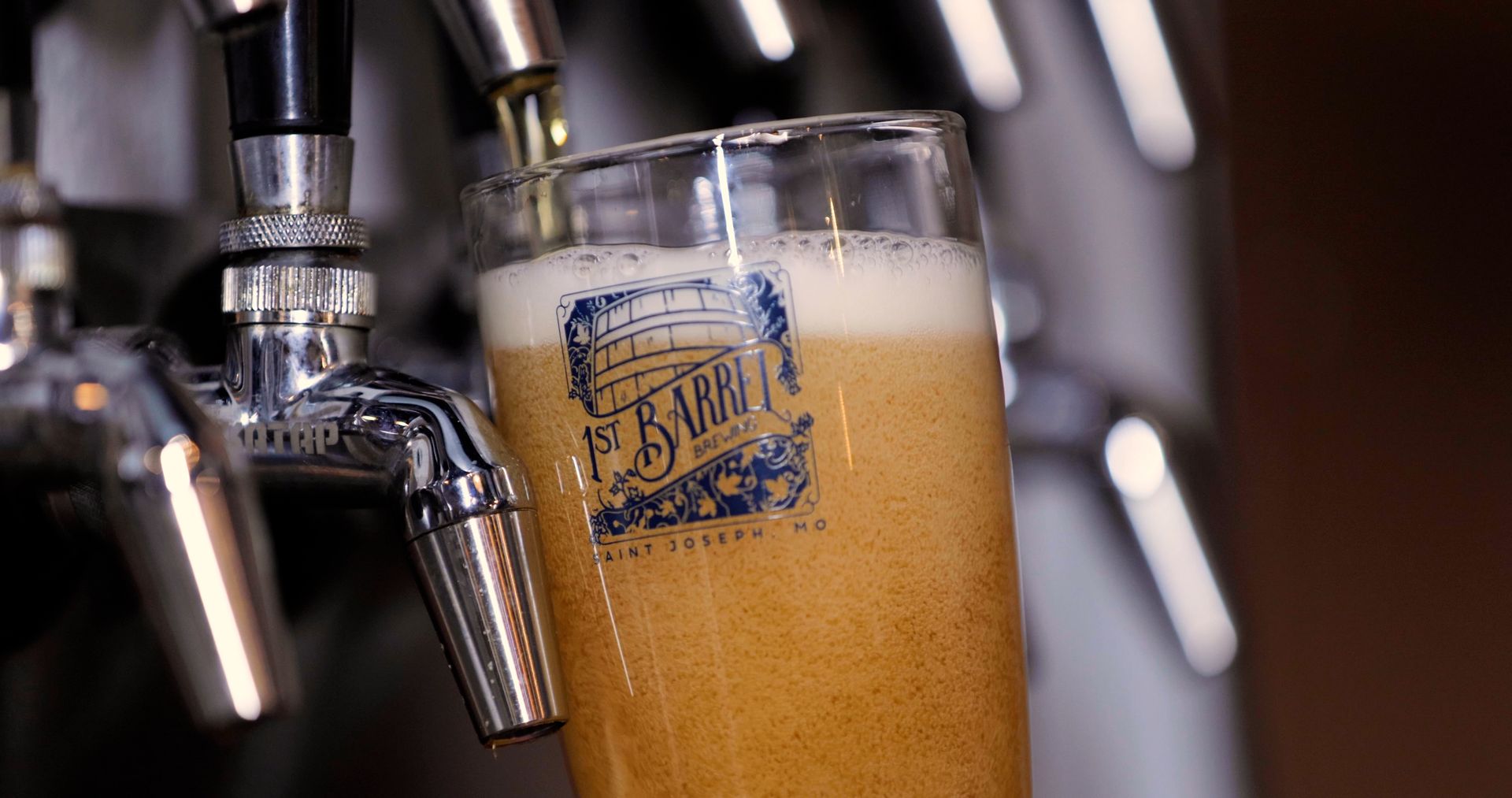 A glass of beer is being poured from a tap.