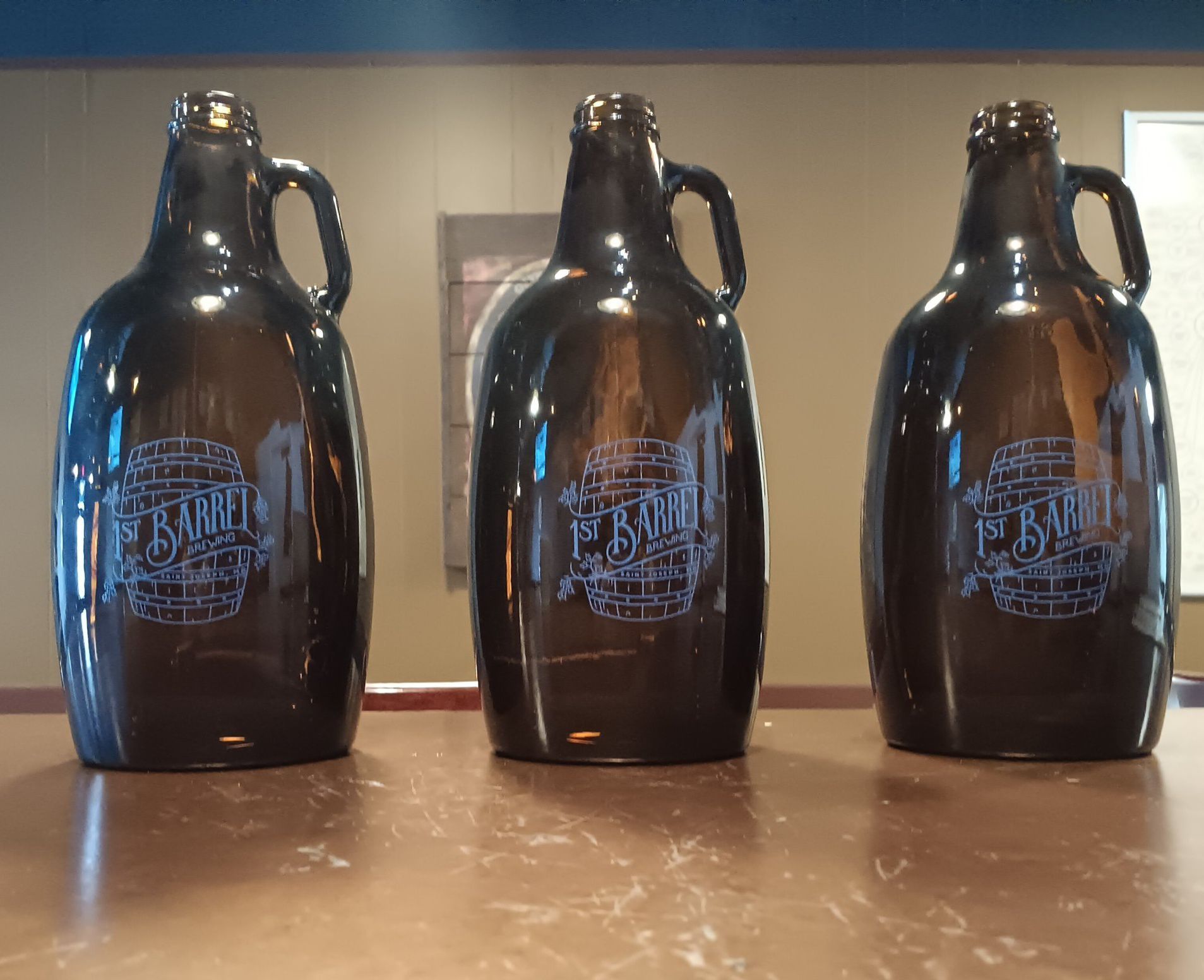 Three pitchers of beer are sitting on a counter.