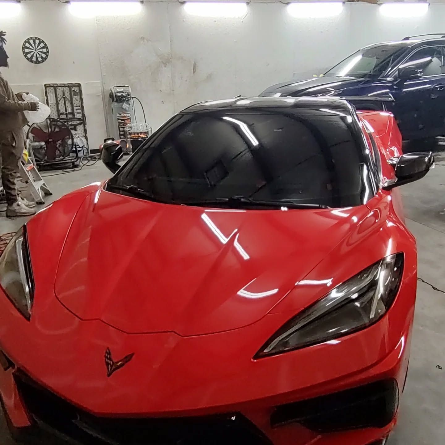 Bright red sports car with black roof inside a garage.