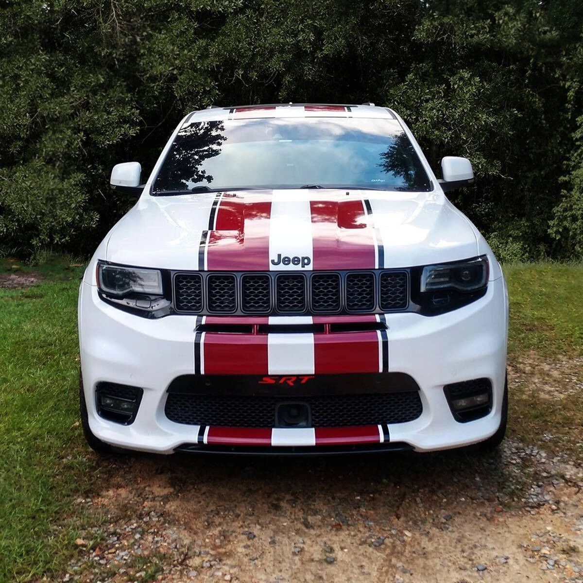 White Jeep Grand Cherokee SRT with red stripes on the hood and grille, parked outdoors.