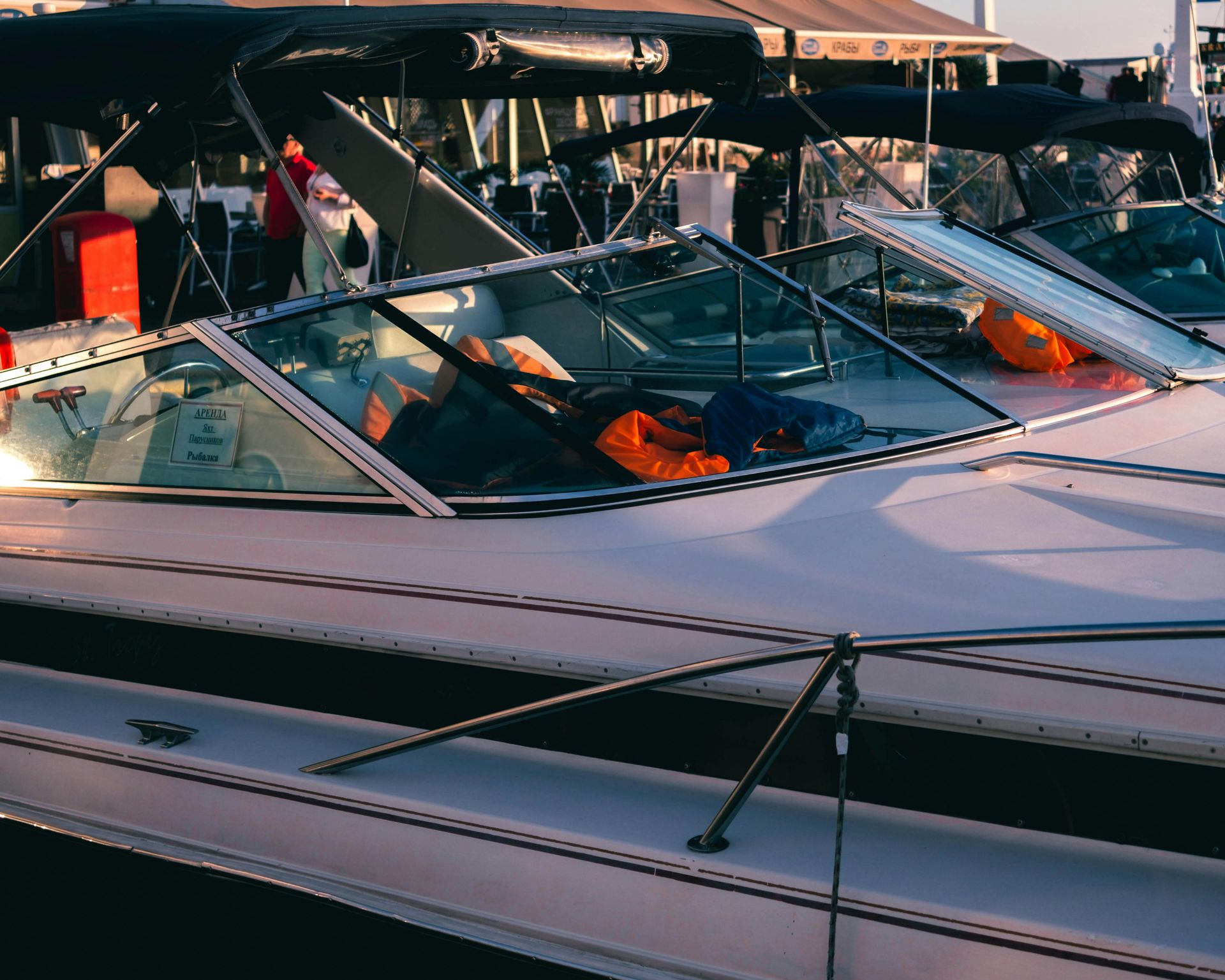 Boats docked at a marina. White hulls, blue and orange life preservers visible, setting sun.