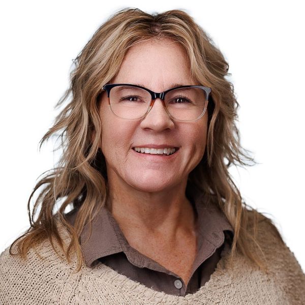 A man is holding a dog in his arms and the dog is wearing a sweater.