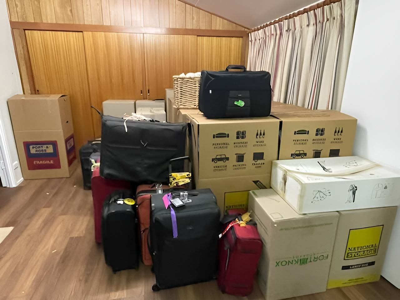 Luggage and Cardboard Boxes Stacked in a Room, Likely for Moving — JR Removals Mackay In Nebo, QLD