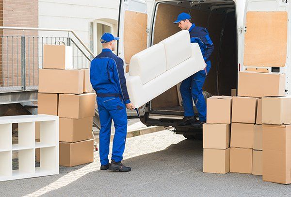 Young Male Movers Unloading Sofa from Truck on Street — JR Removals Mackay in Mackay, QLD