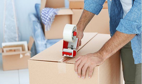 Closeup of Man Packing Cardboard Box — JR Removals Mackay in Mackay, QLD Closeup of Man Packing Cardboard Box — JR Removals Mackay in Mackay, QLD