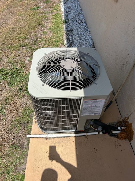 An air conditioner is sitting on a sidewalk next to a wall.