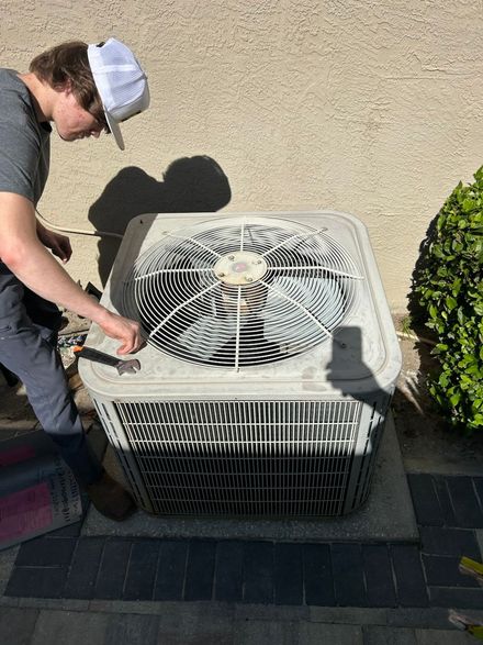 A man is working on an air conditioner outside of a building.