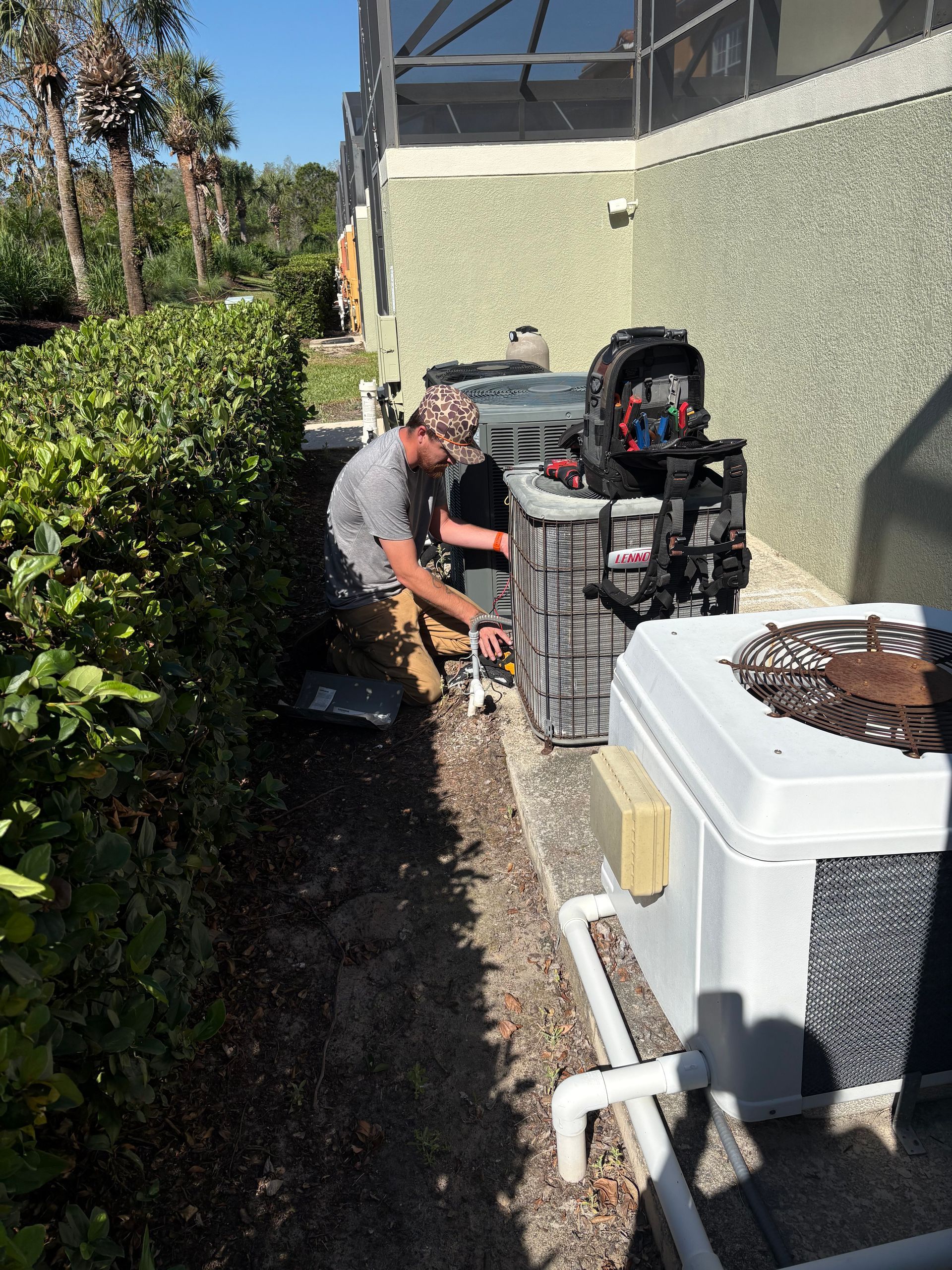 A man is working on an air conditioner outside of a building.