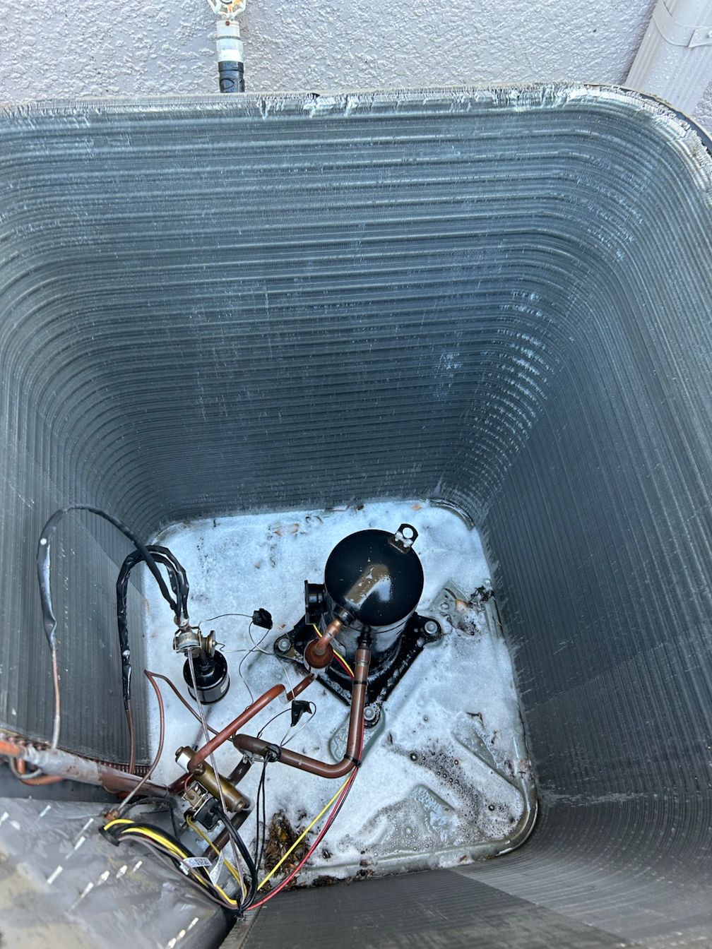 A close up of a dirty air conditioner with a compressor inside of it.