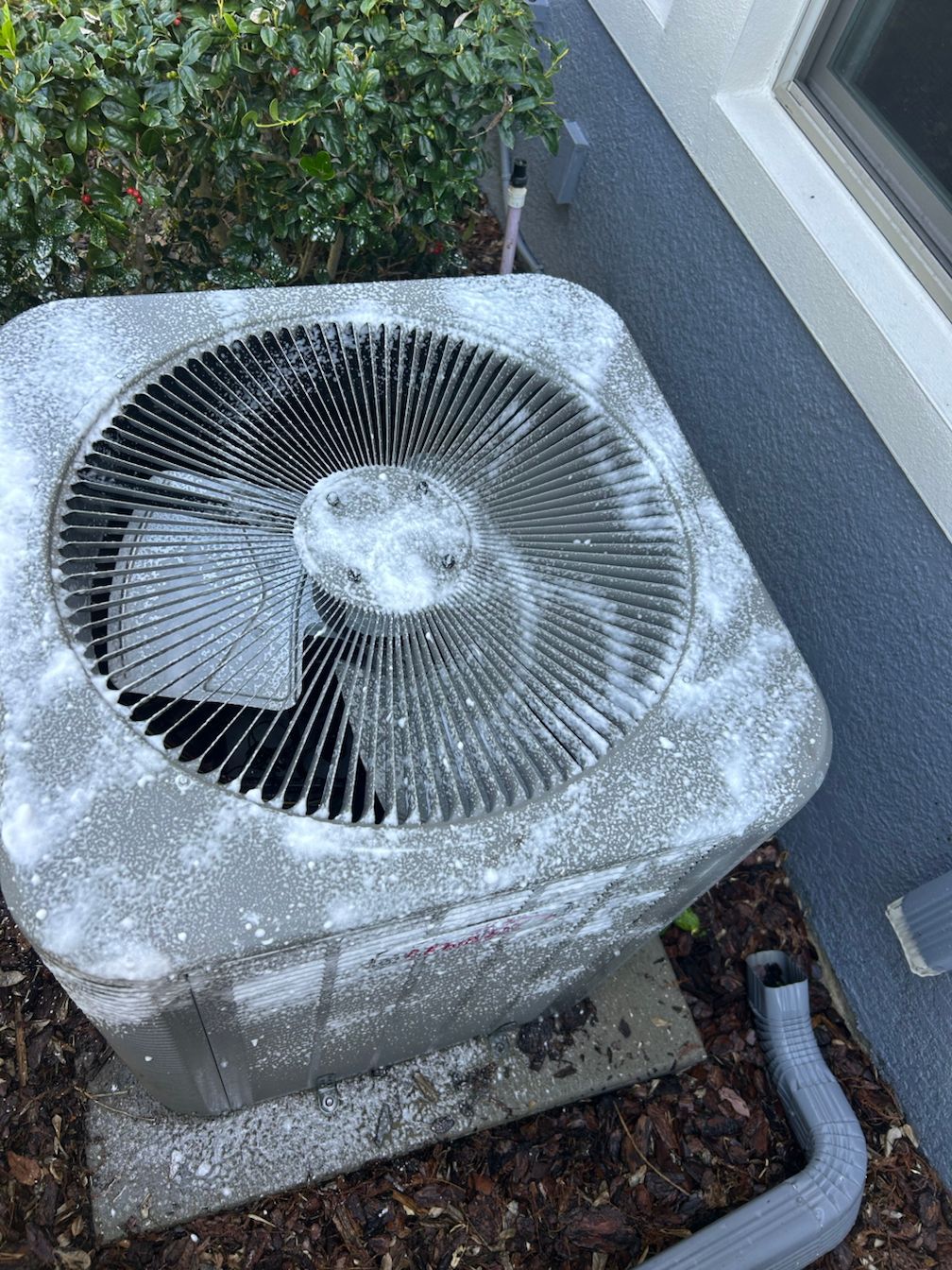 A dirty air conditioner is sitting on the side of a house.