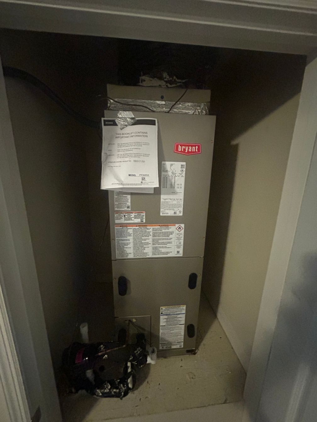 A furnace is sitting in a closet next to a door.