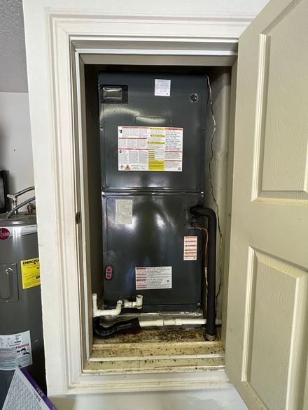 An air conditioner is sitting inside of a doorway in a room.