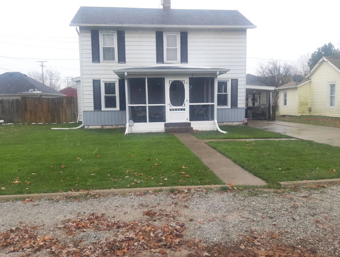 White two-story house with screen porch, blue accents, and green lawn. Gray sidewalk leads to the front door.