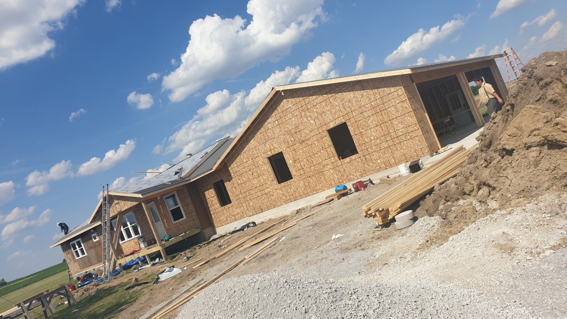 Construction site: a house under construction against a blue sky with fluffy clouds.