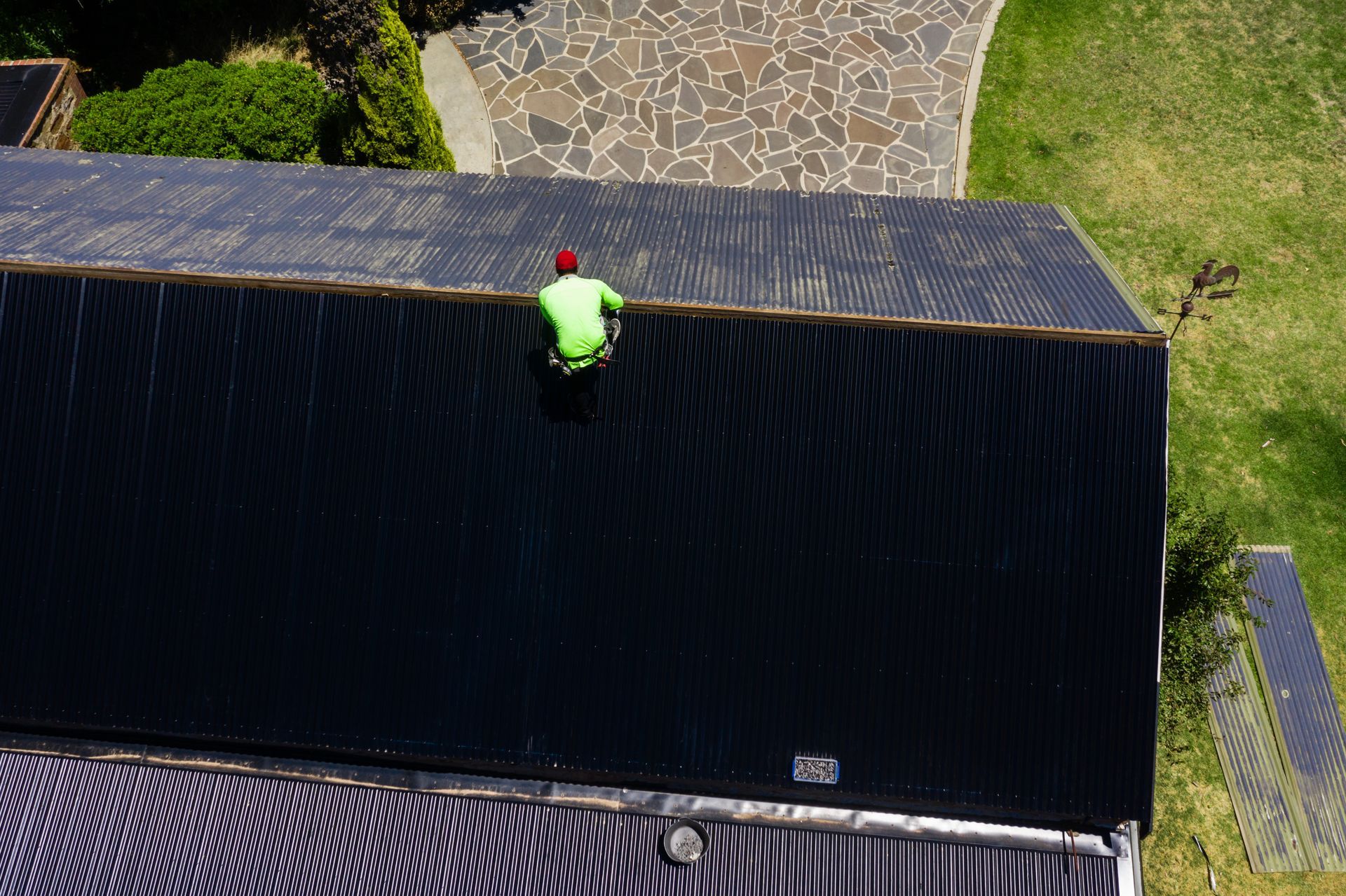 A roofing professional on top of a house, installing shingles with precision and focus.
