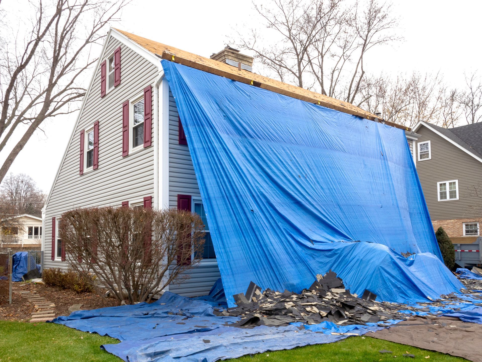 A pile of shingles lying on a tarp during a roof replacement.