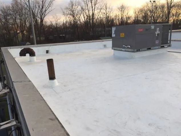 White flat commercial rooftop with vents and an HVAC unit.