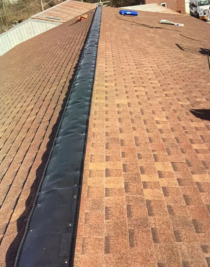 A brown shingle roof with a dark valley; a person is on the roof.