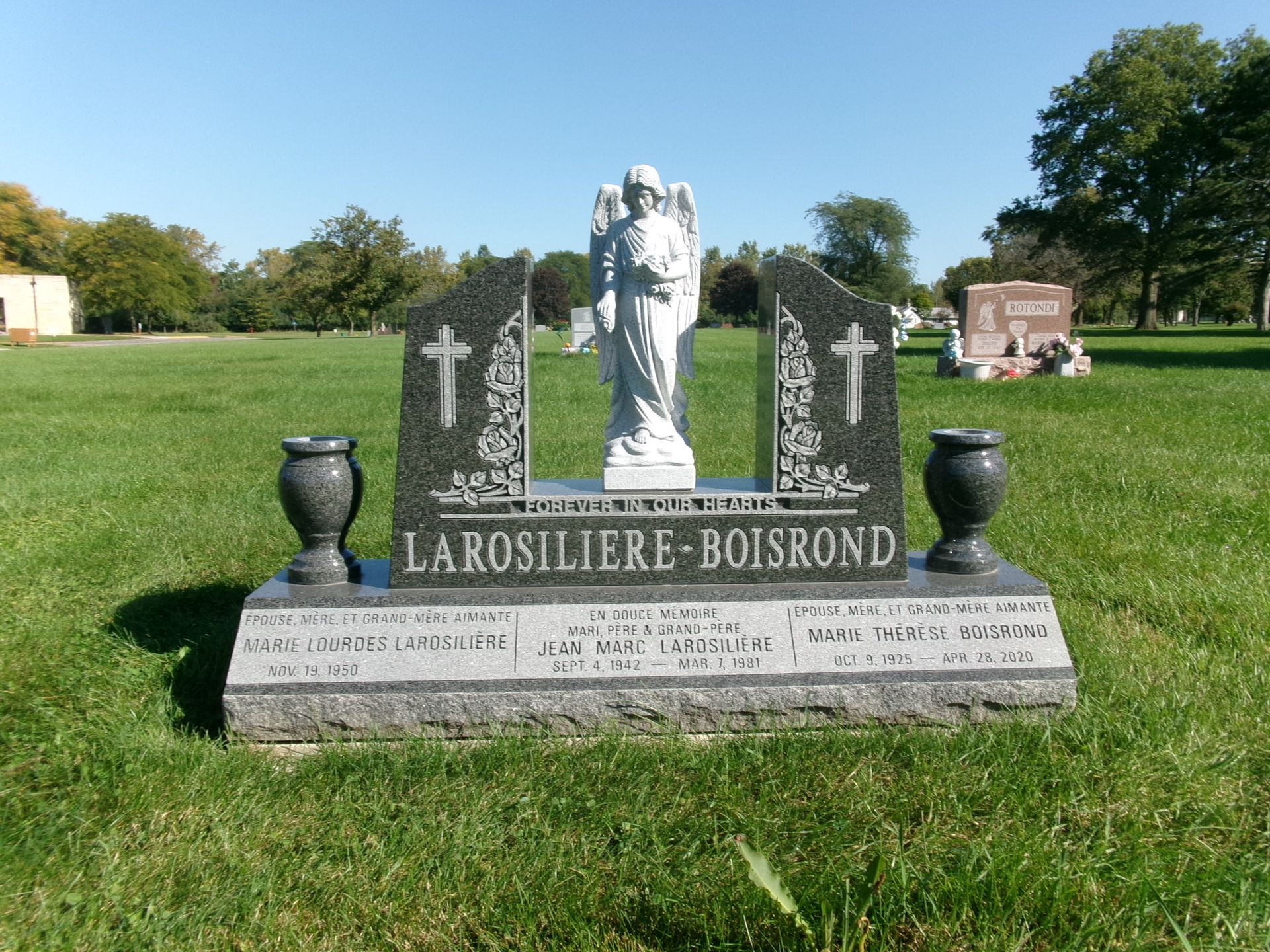 A black granite gravestone with a central angel statue, engraved with the names LAROSILIERE-BOISROND in a grassy cemetery.