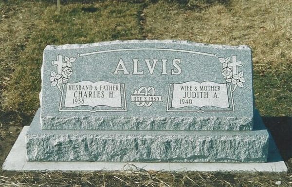 Headstone for Charles II (1933) and Judith A. Alvis (1940). Gray granite with engraved text, cross and floral accents.