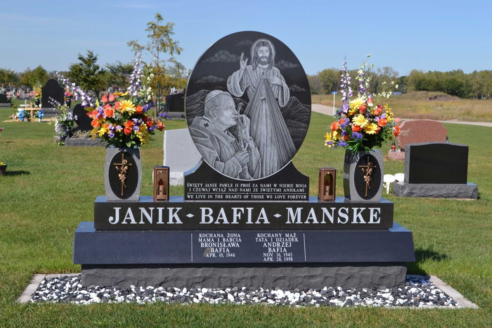 Gravestone with religious imagery and floral arrangements in a cemetery.