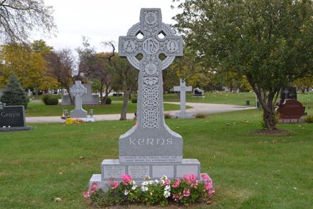 Stone mausoleum, "Tibstra" inscribed above door. Bronze door with cross, flanked by columns and hedges.