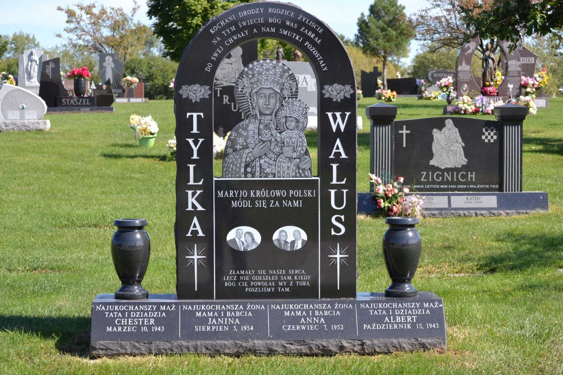 Black granite headstone in a cemetery, with an etched image of a religious figure and two vases.
