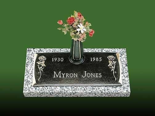 Grave marker for Myron Jones, born 1930, died 1985. Features a floral arrangement and a black granite plaque.