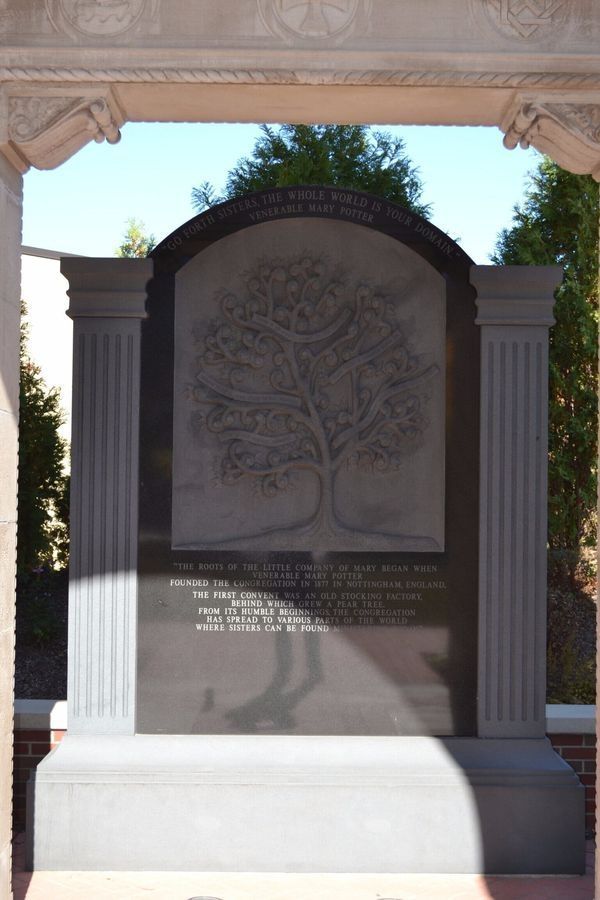 Monument with a tree carving and text, framed by columns.