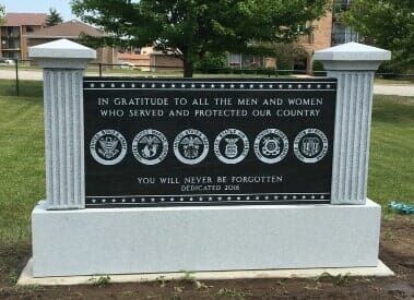 Memorial monument with text honoring U.S. military service members. Includes service emblems, text and a dedication date.
