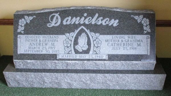 Gravestone of Andrew M. and Catherine M. Danielson. It's gray granite with an engraved cross and praying hands.