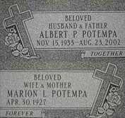 Blank gray headstone with decorative crosses and a curved top in a grassy cemetery.