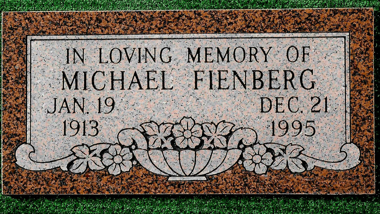 A rectangular granite grave marker for Michael Fienberg, born Jan 19, 1913, and died Dec 21, 1995, with a floral design.