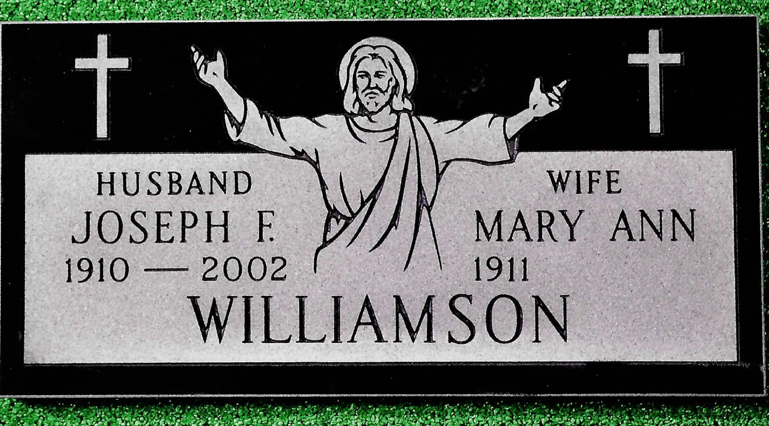 A black and grey tombstone for Joseph F. (1910–2002) and Mary Ann Williamson (1911–), featuring a central figure of Jesus.