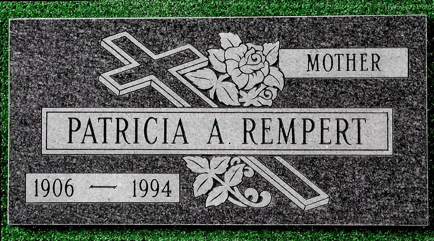 A flat gray granite grave marker for Patricia A. Rempert, dated 1906–1994, featuring a cross and rose engraving.