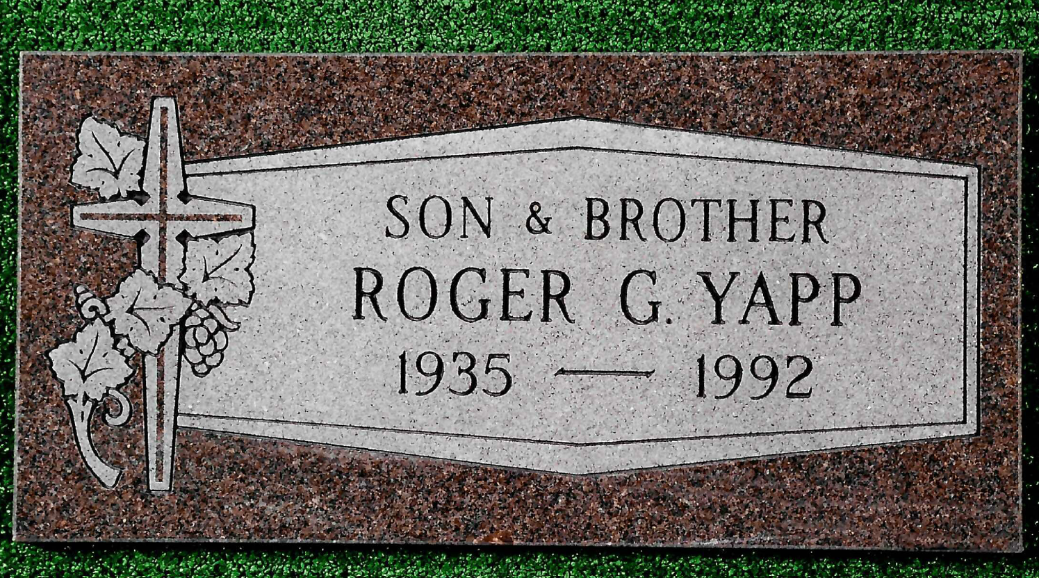 A rectangular granite grave marker for Roger G. Yapp, 1935–1992, featuring a cross and vine carving on the left.