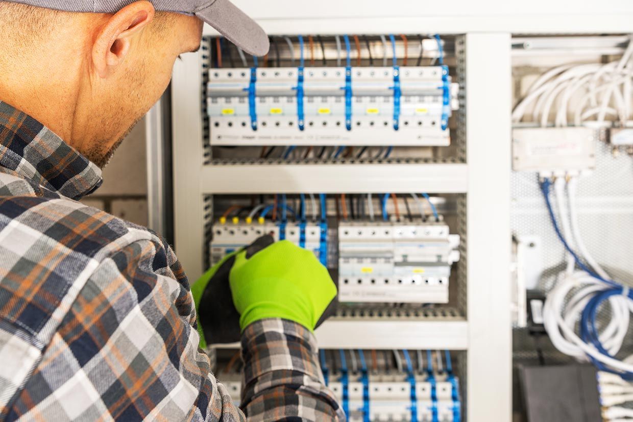A Man in a Plaid Shirt is Working on an Electrical Box — Brite-Lec Pty Ltd in Currajong, QLD