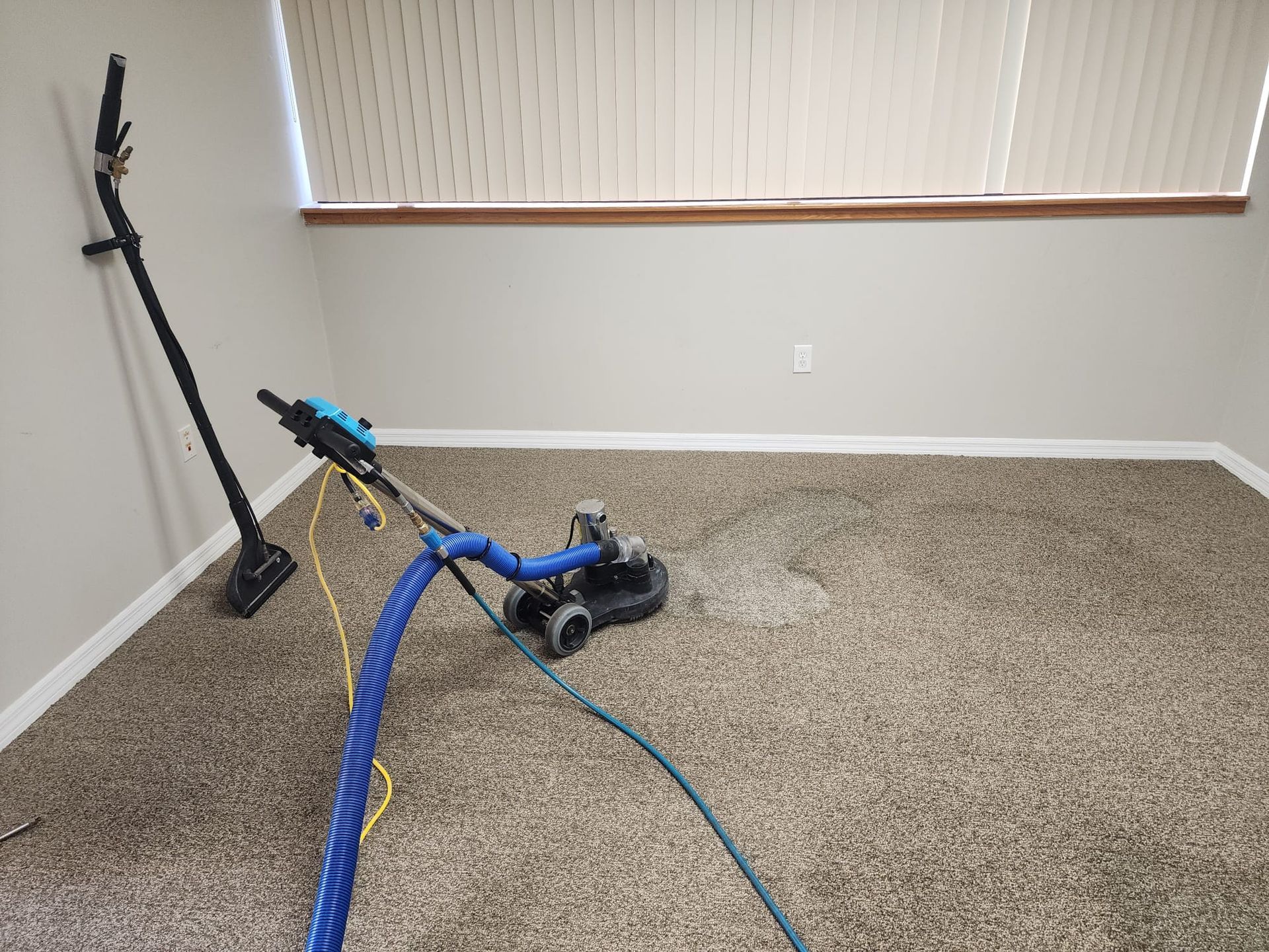 A machine is cleaning a concrete floor in a room.