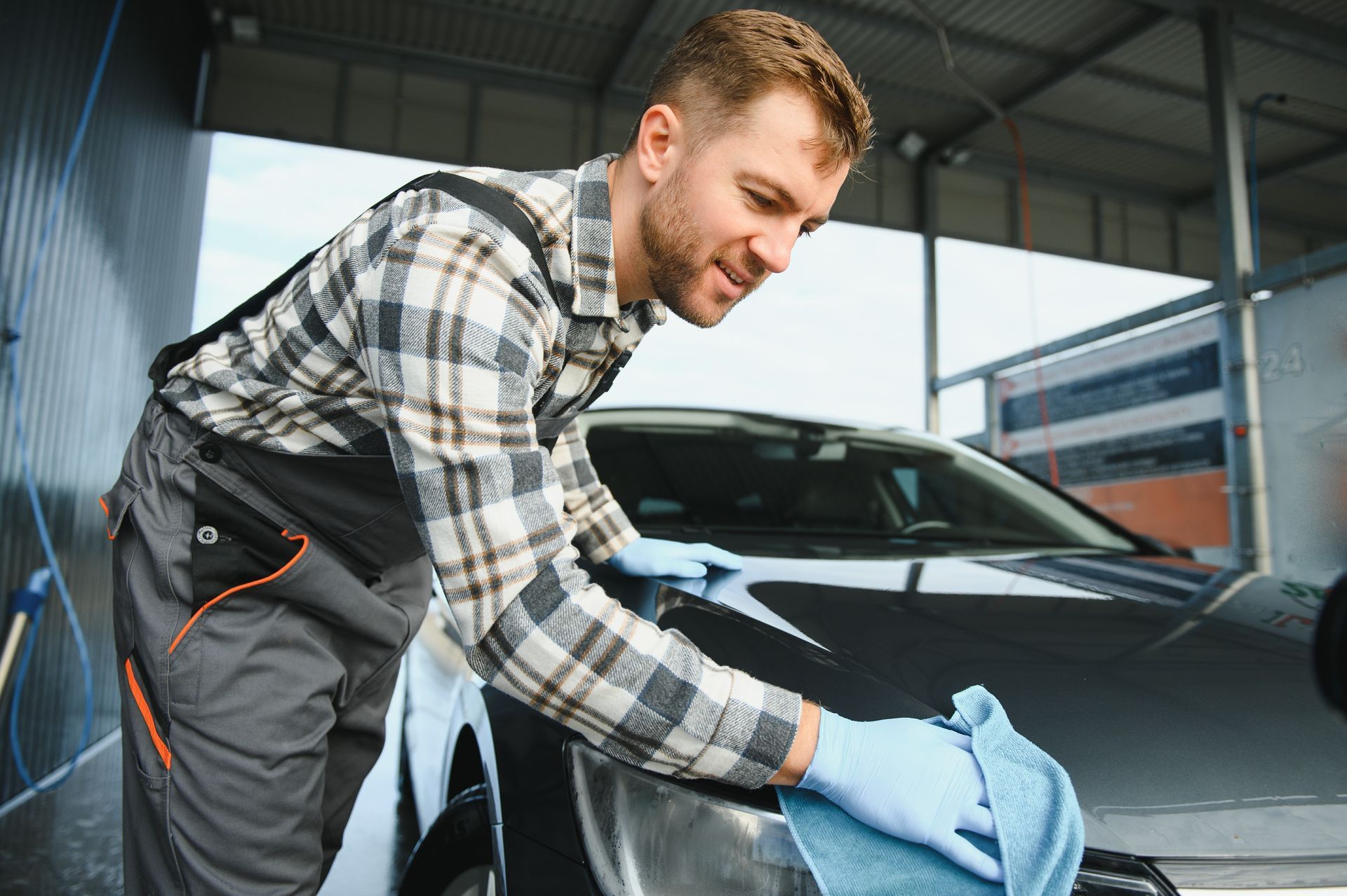 A mechanic cleaning a recently repaired car with a microfiber cloth. A mechanic cleaning a recently repaired car with a microfiber cloth.