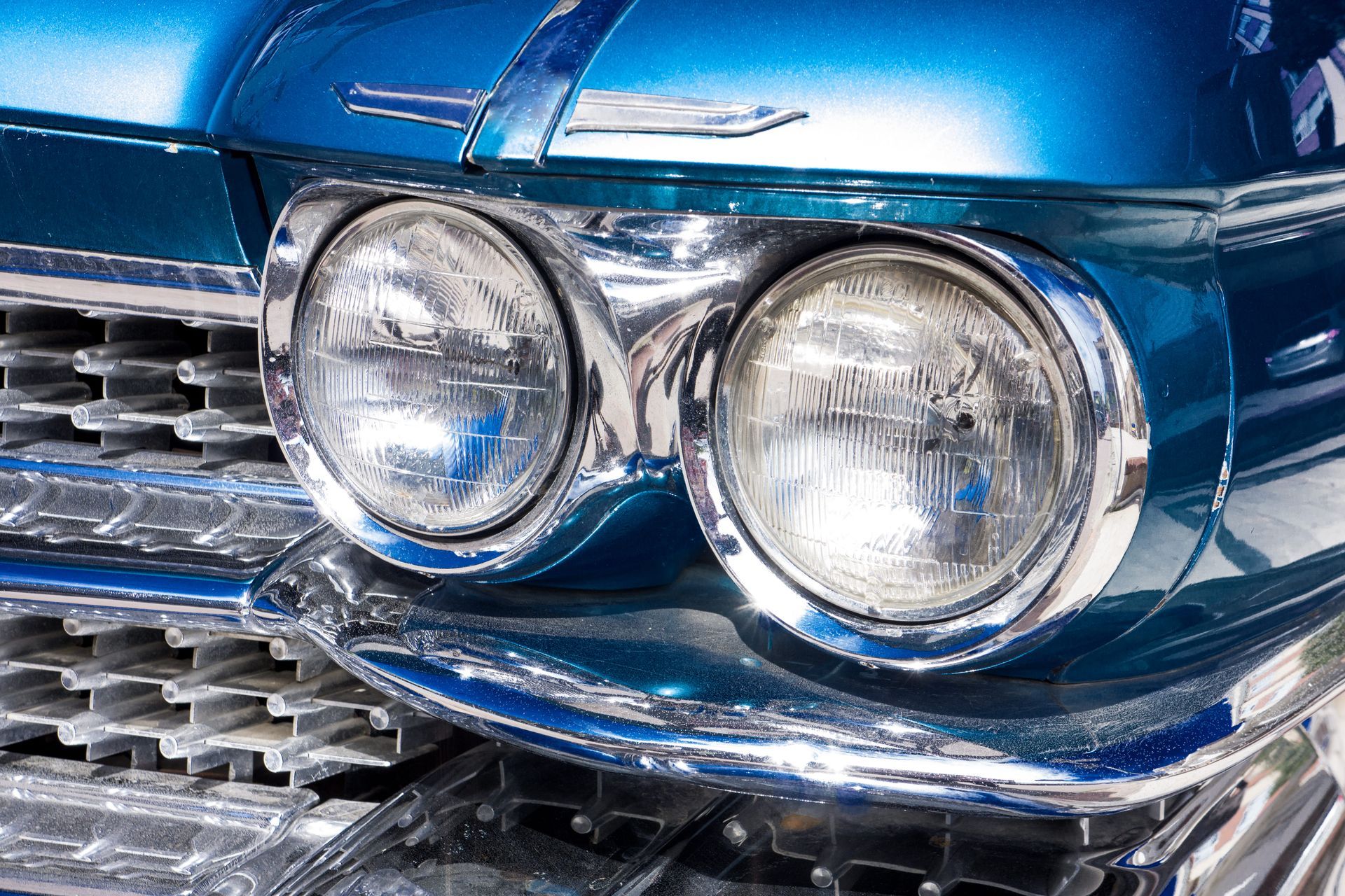 A close-up of a vintage blue car’s front detail.