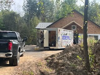 Two trucks are parked in front of a trailer that says ideal.