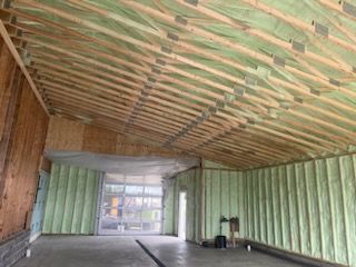 The inside of a building under construction with green insulation and wooden beams.
