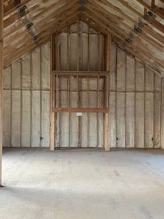 A large empty room with a wooden ceiling and walls covered in insulation.