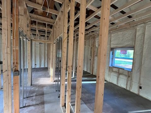 The inside of a house under construction with wooden beams and insulation.