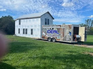 A trailer is parked in front of a house that is being built.